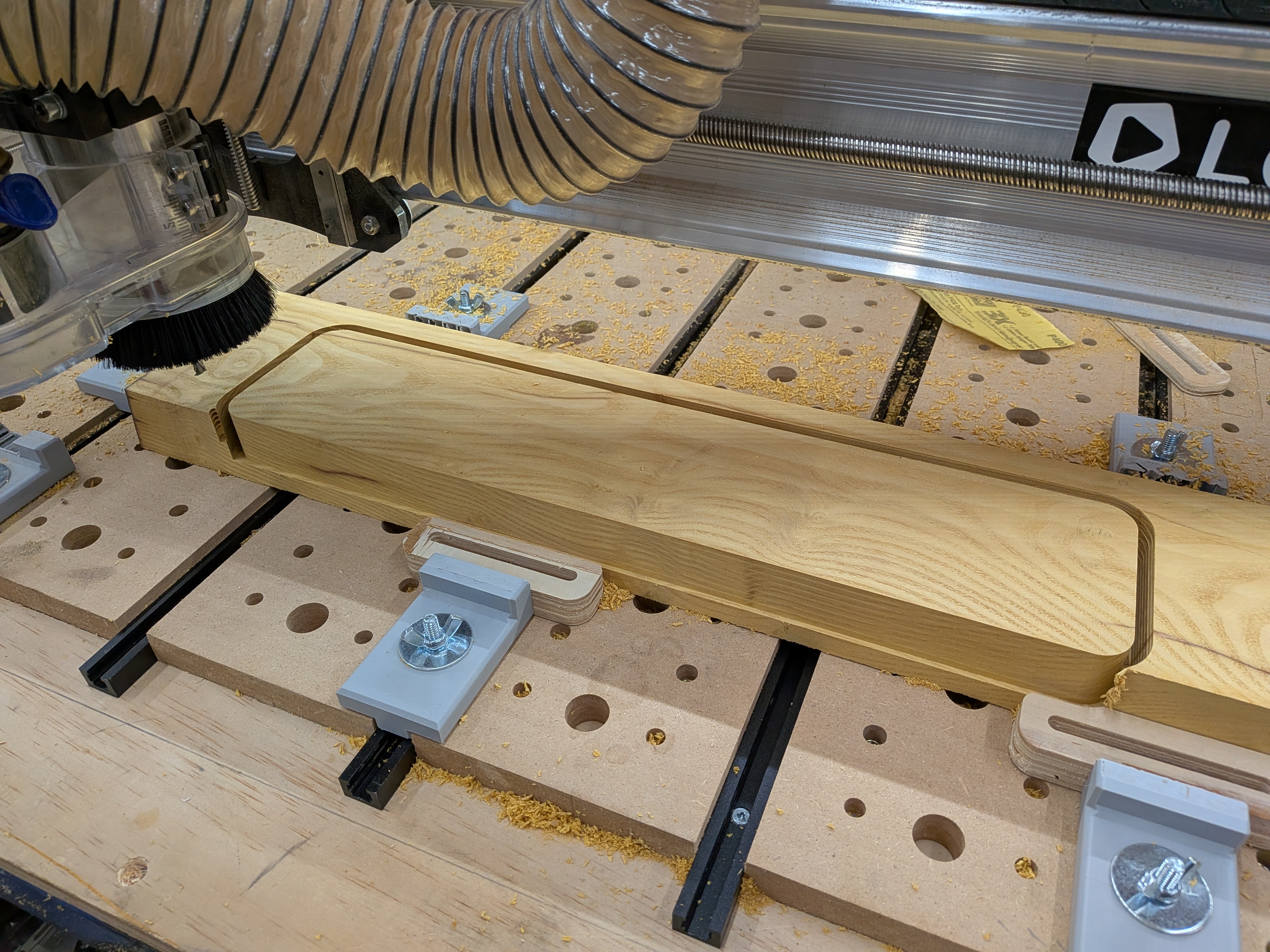 Spalted maple bed on the CNC after routing the handle pocket and brass disc recess